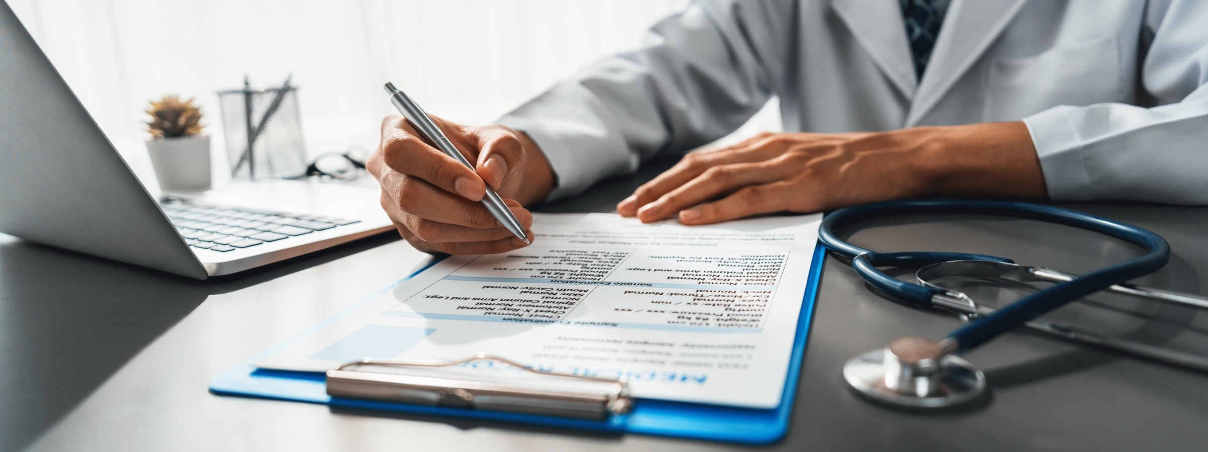 Reviewer annotating a tabbed medical record with a stethoscope nearby