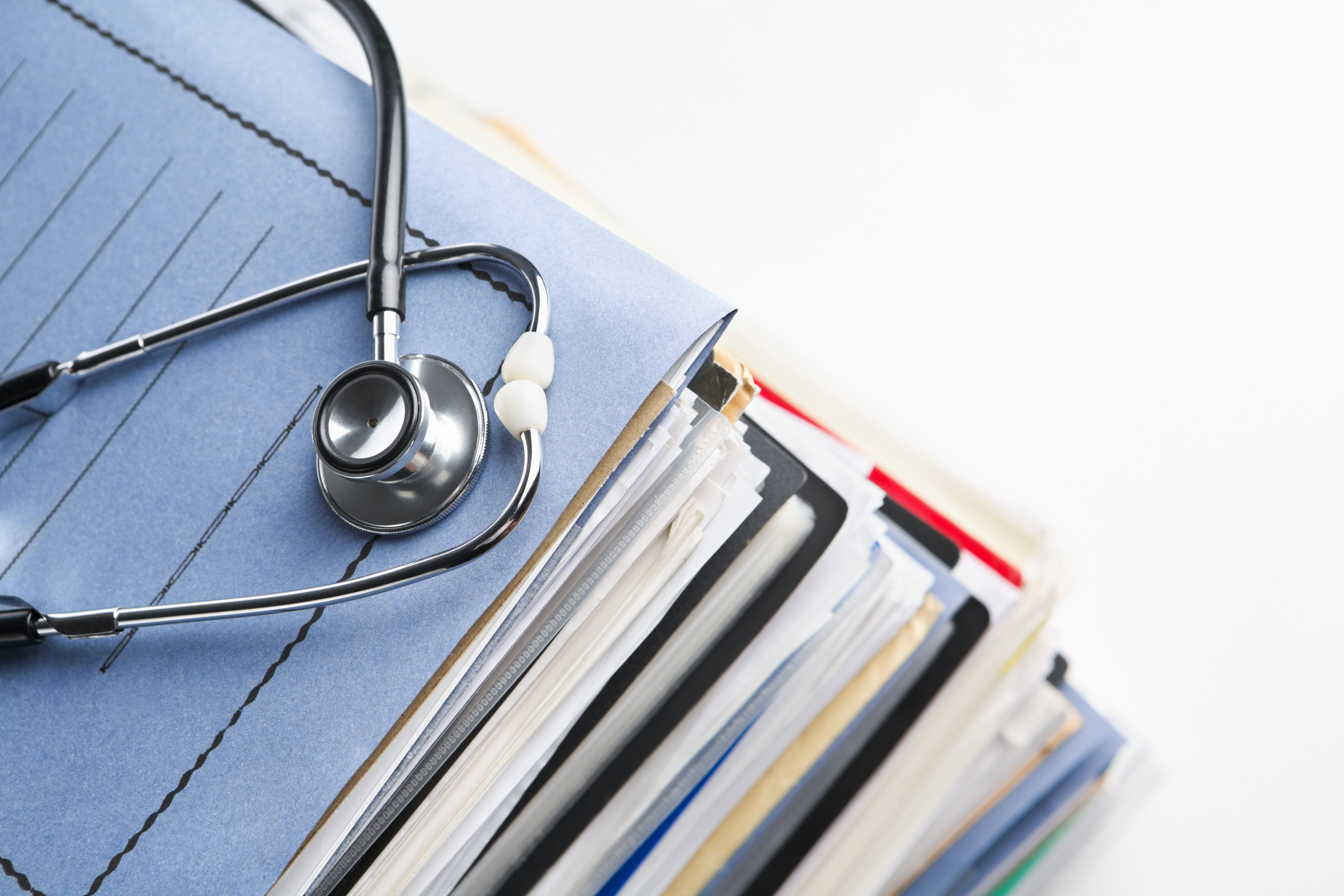 Stethoscope resting on a stack of medical record files